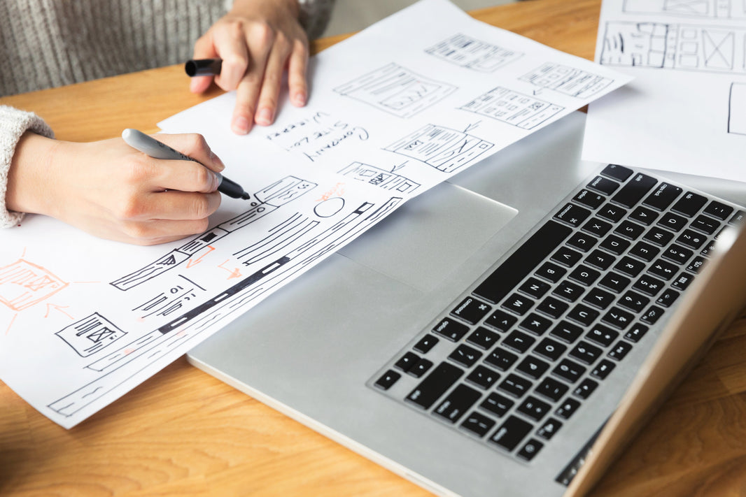 person taking notes next to laptop