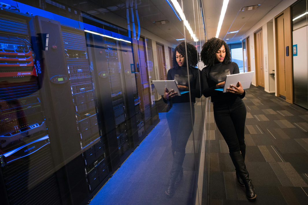 woman typing on laptop next to server