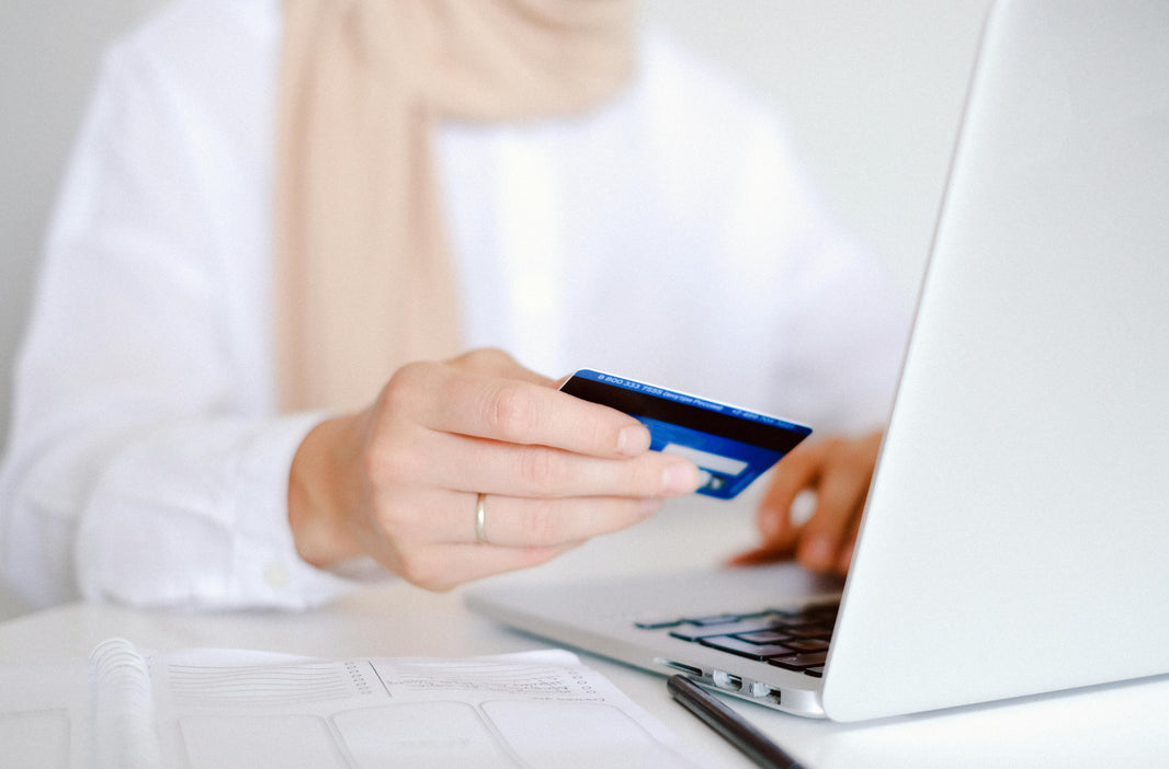 woman holding credit card typing on laptop