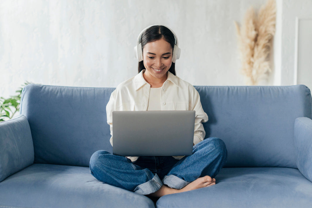 woman smiling wearing headphones looking at computer