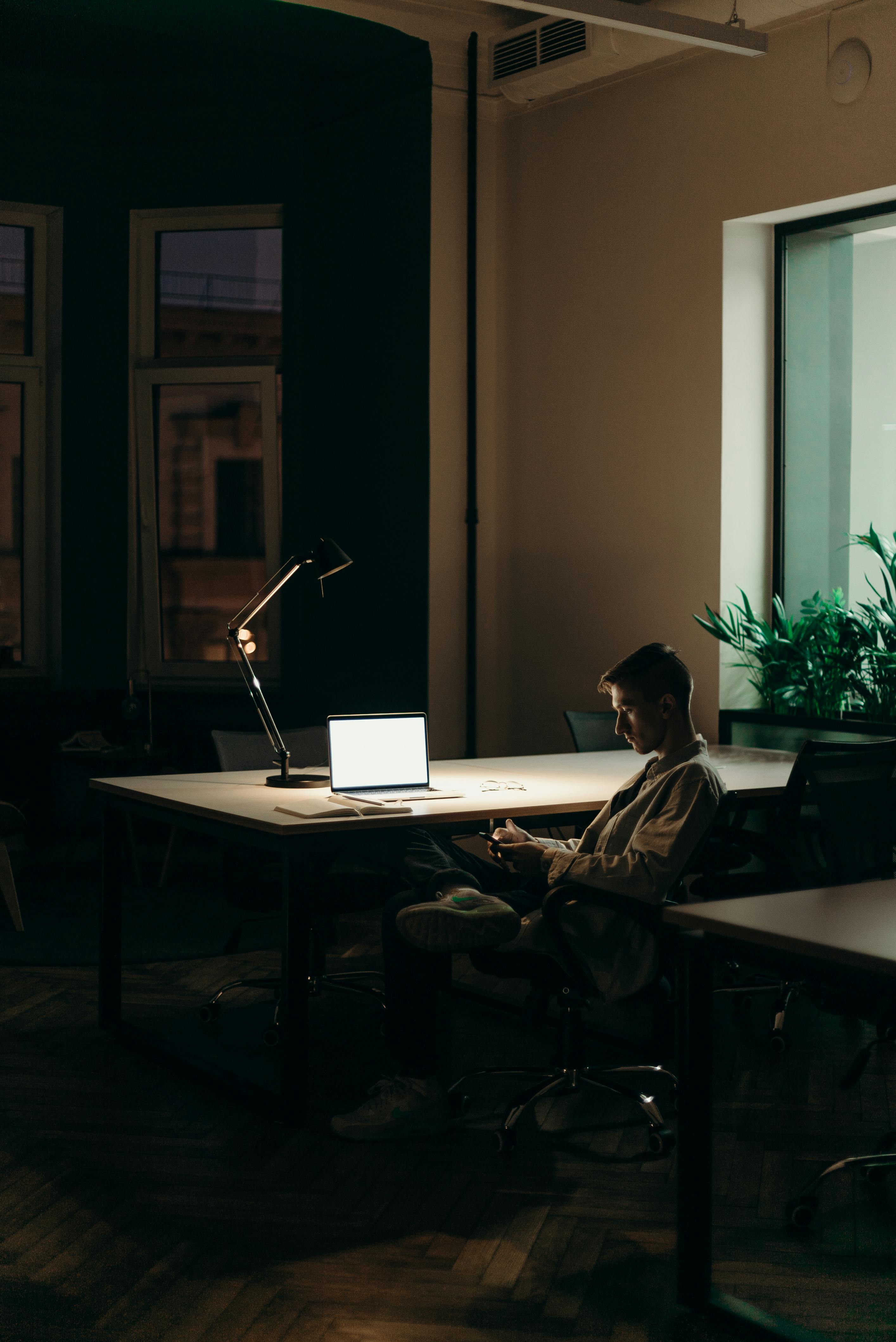 man sitting at desk looking at mobile device