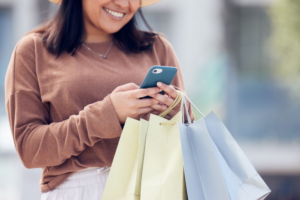 woman holding shopping bags and using cellphone