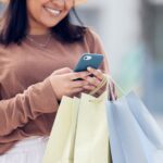woman holding shopping bags and using cellphone
