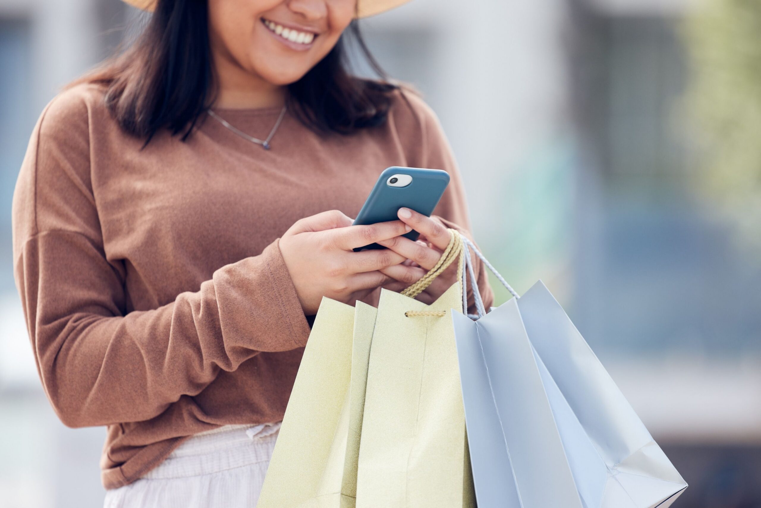 woman holding shopping bags and using cellphone
