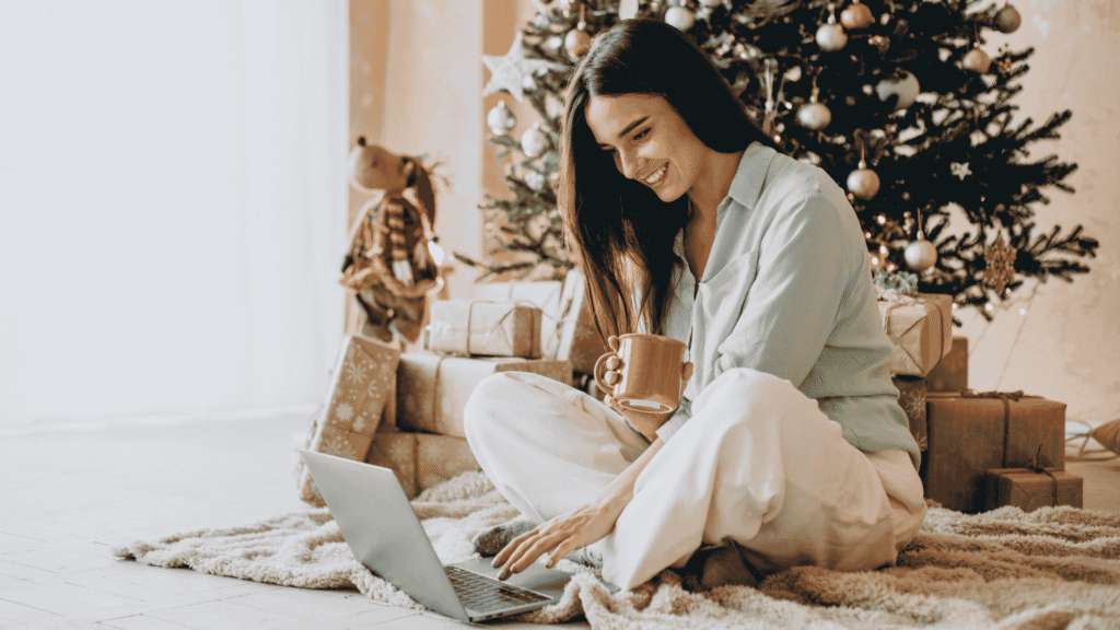 Woman shopping on laptop in front of Christmas tree