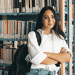 student standing by bookshelf