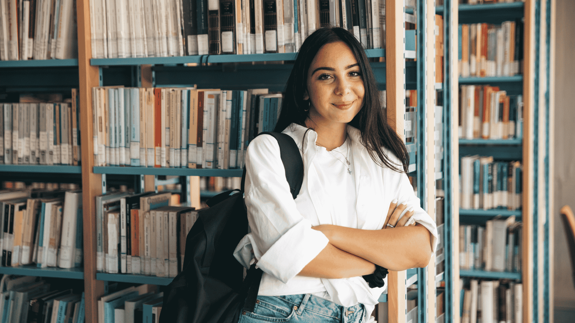 student standing by bookshelf