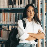 student standing by bookshelf