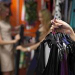woman holding hangers of clothing