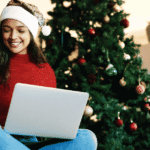 Woman smiling shopping online in front of Christmas tree